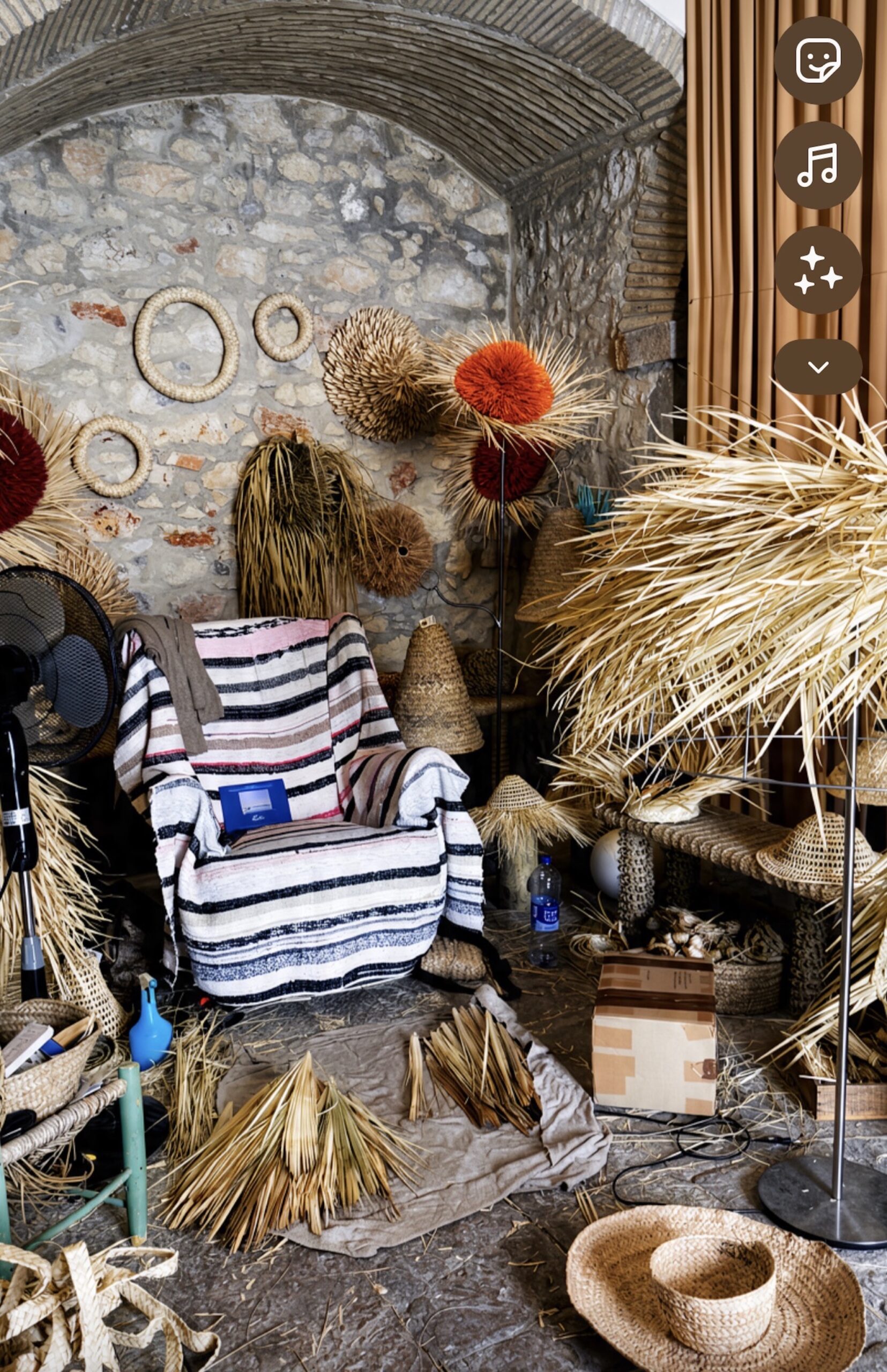Woven roundels and dyed palm pompoms on a stone wall in the workshop