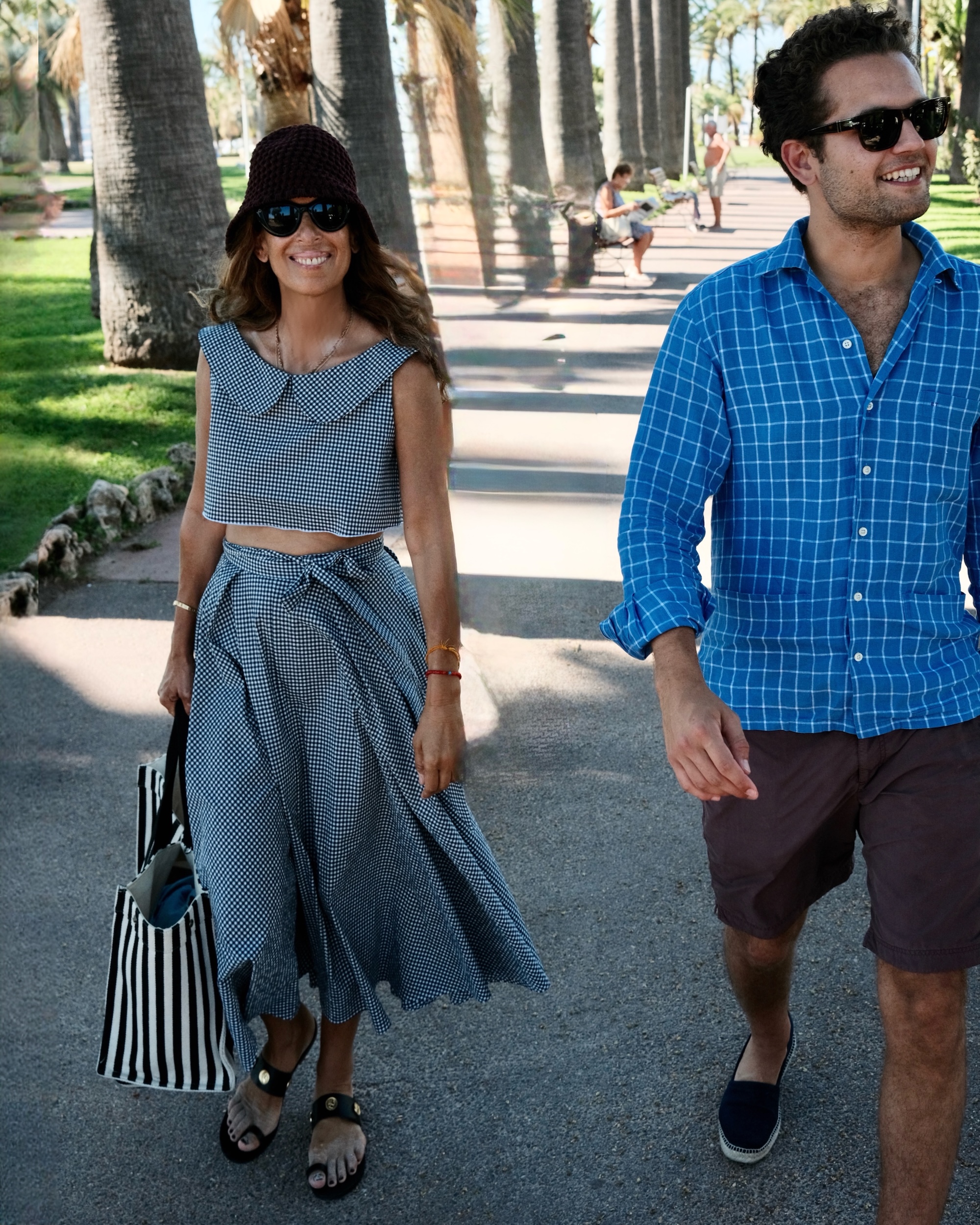 Couple walking under palm trees on a summer promenade