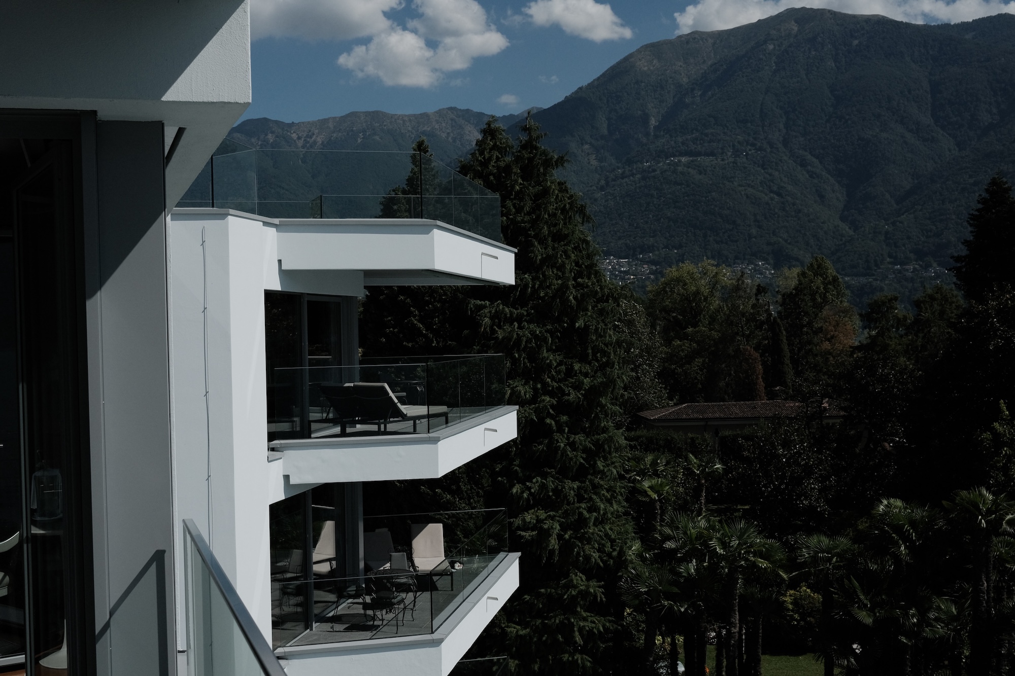 Glazed balconies stacked on the facade of Hotel Eden Roc, mountains behind
