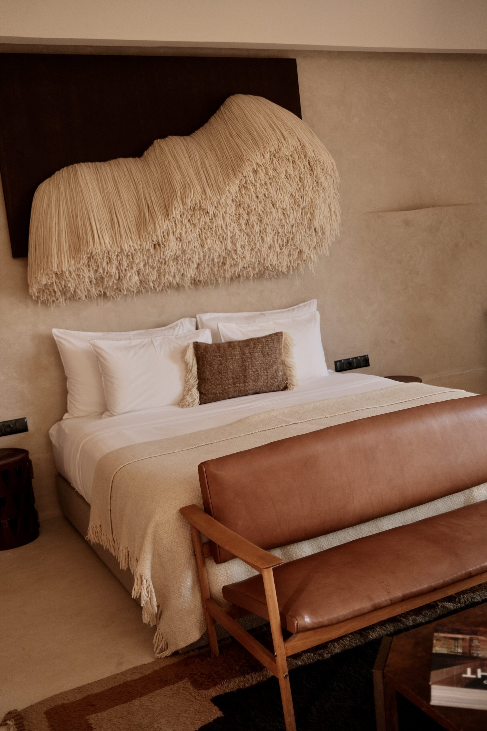 Bed with fringed wool wall sculpture at Farasha Farmhouse