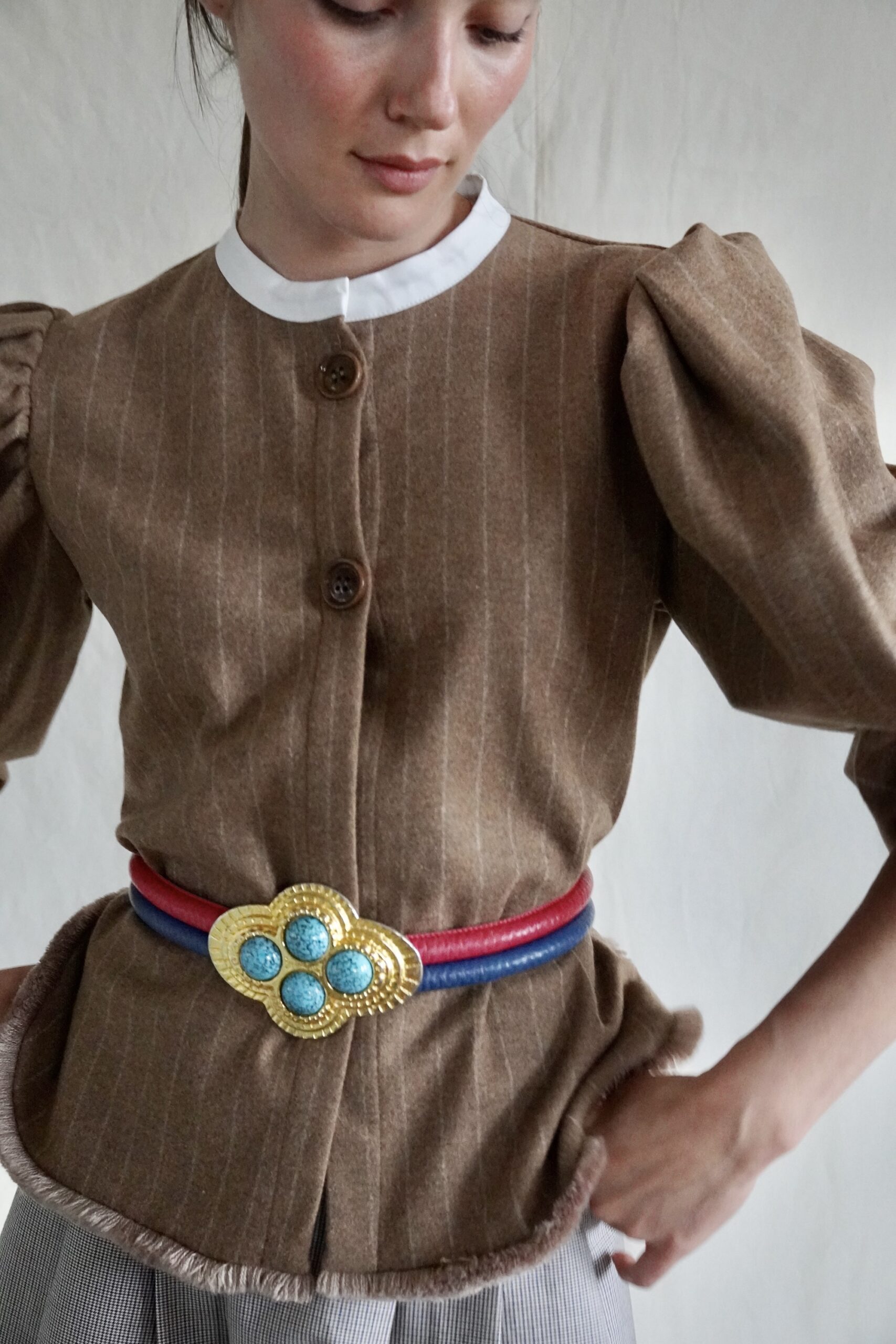 The archive belt buckle worn over a pinstriped wool jacket