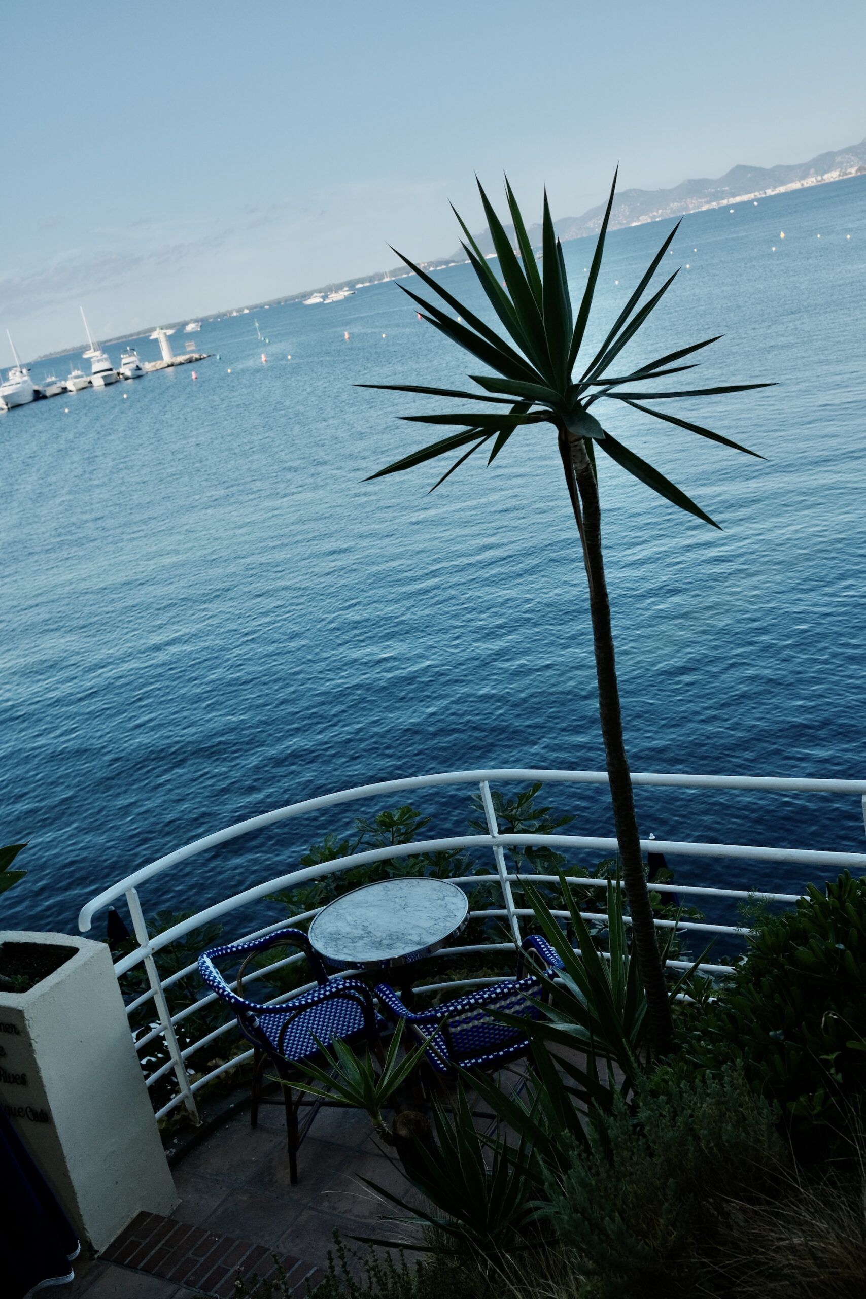 A bistro table for two on a terrace above the sea at Hotel Belles Rives