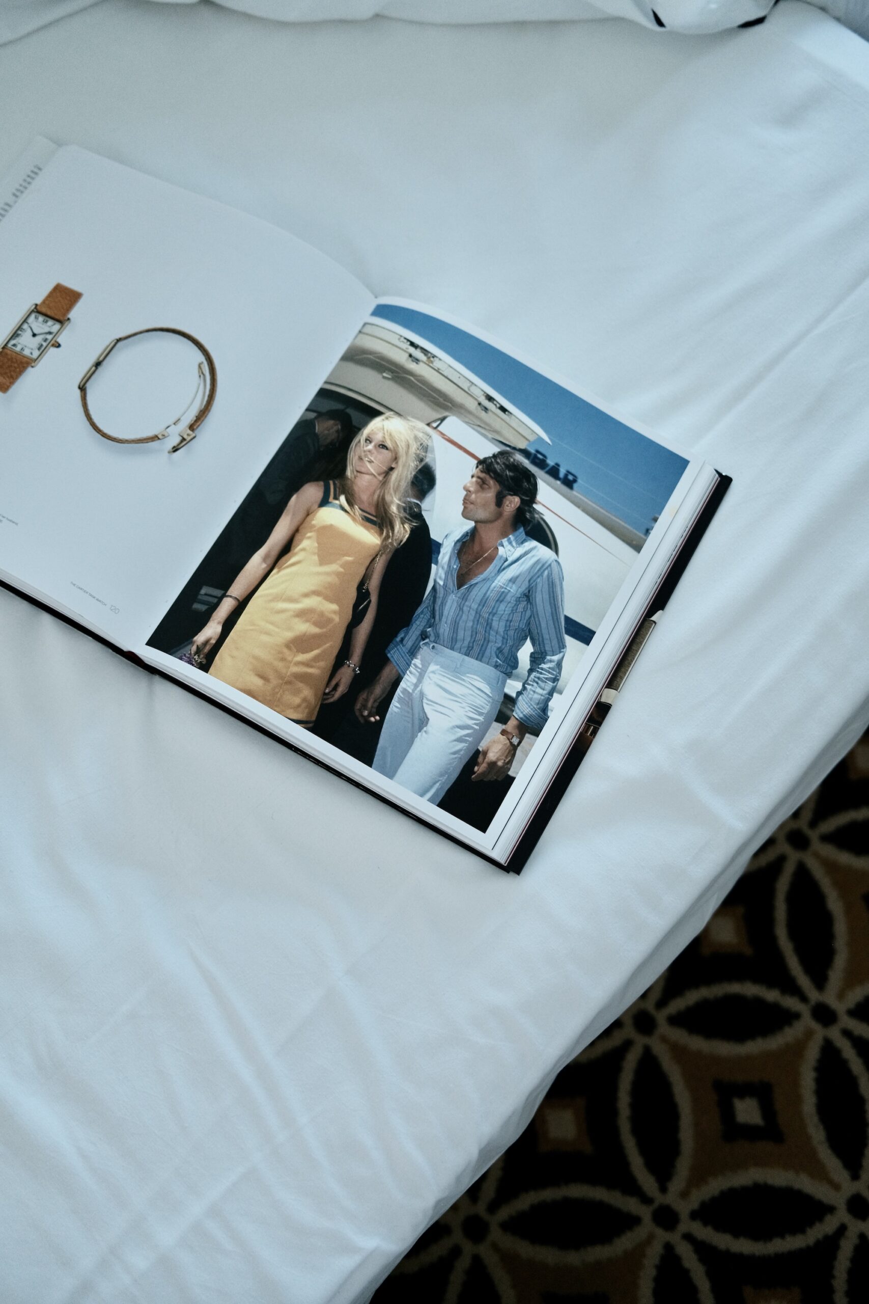 An open photo book with a vintage Riviera image lying on the bed at Hotel Belles Rives