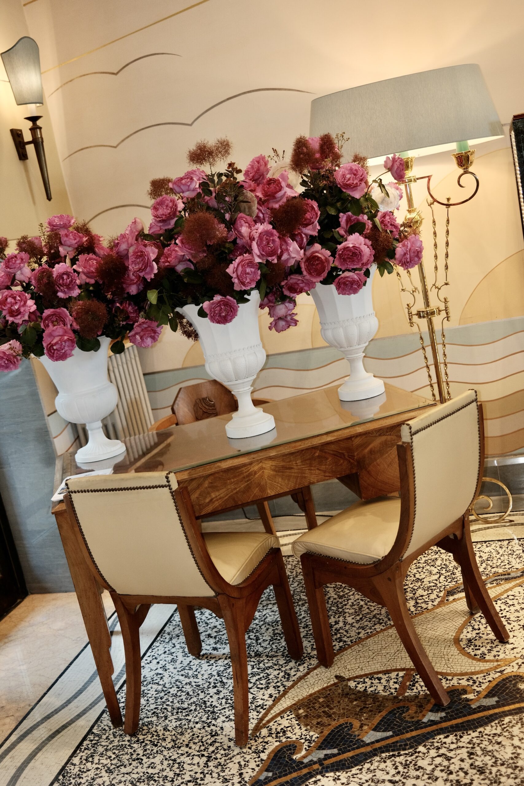 Three urns of pink roses on an Art Deco desk in the lobby of Hotel Belles Rives