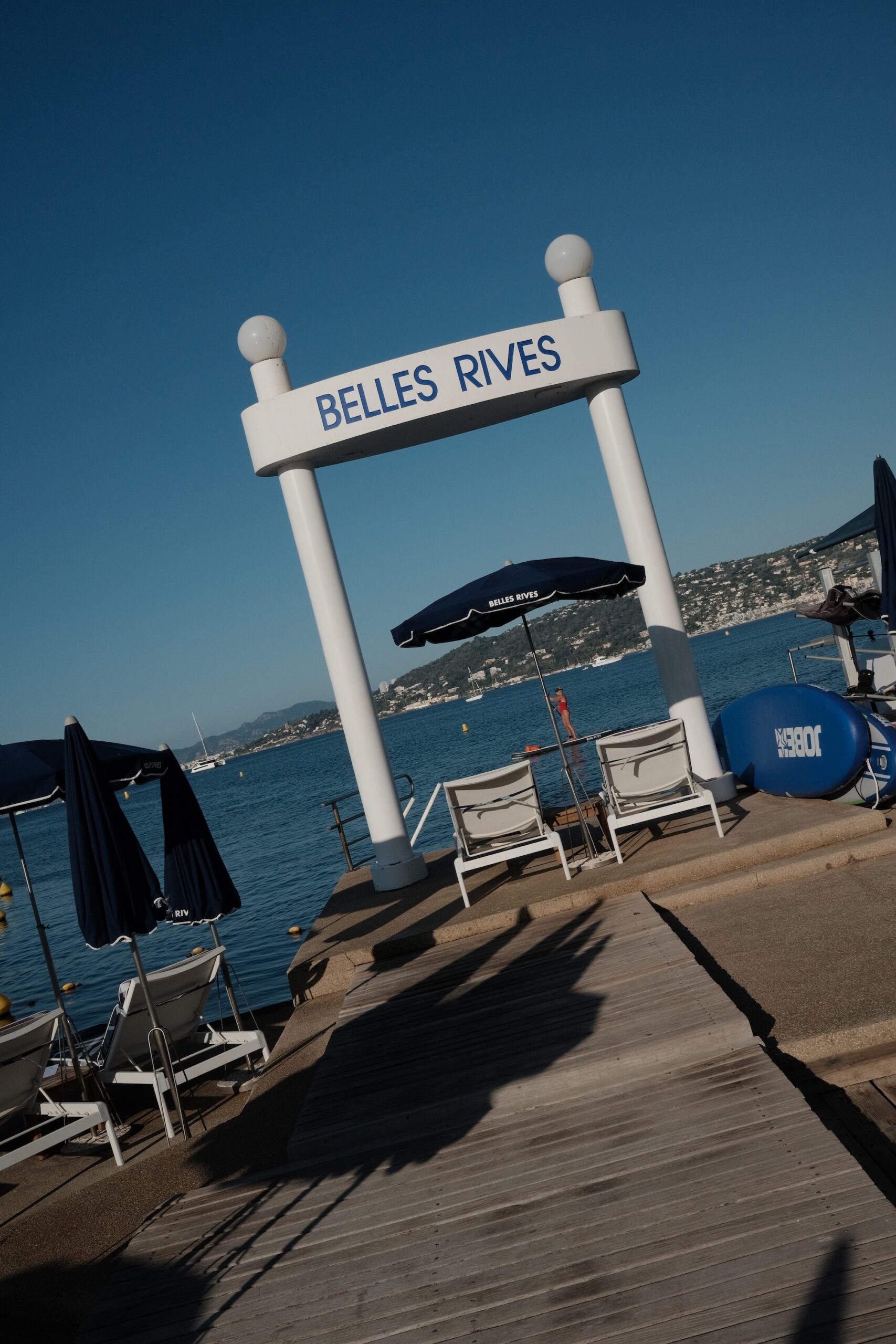 The Belles Rives arch on the hotel's private pontoon with a paddle boarder in the bay